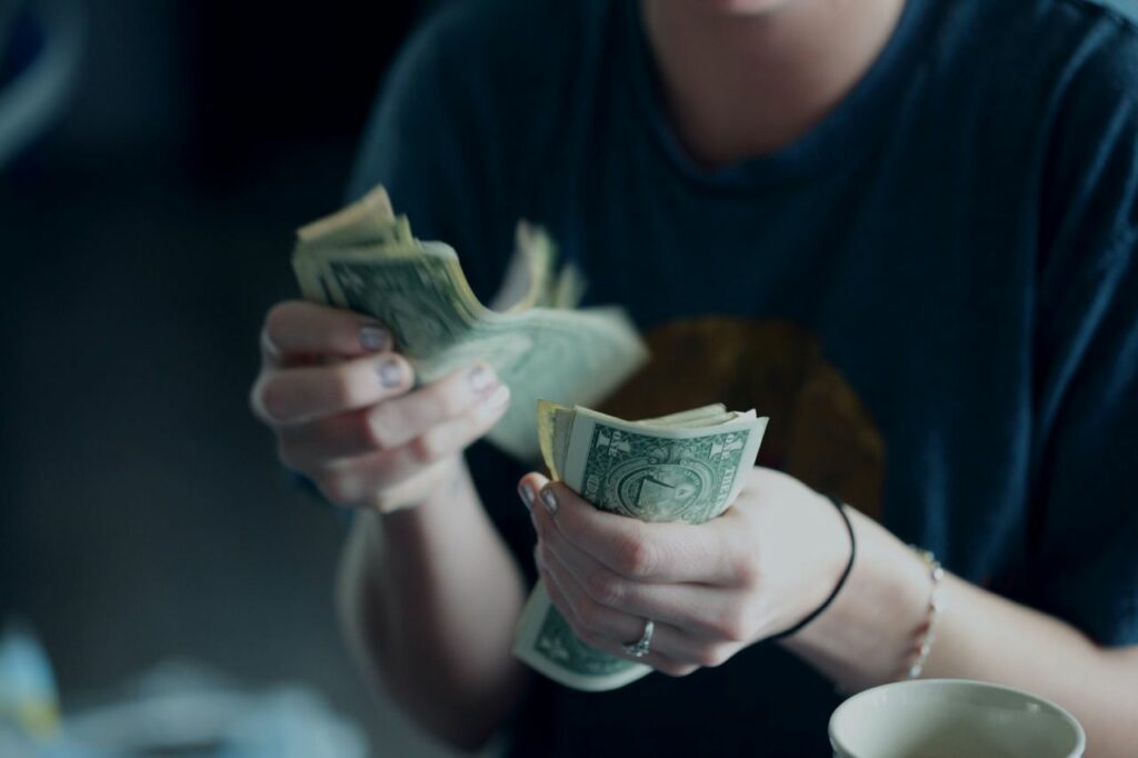 female hands rustling thick stack of cash